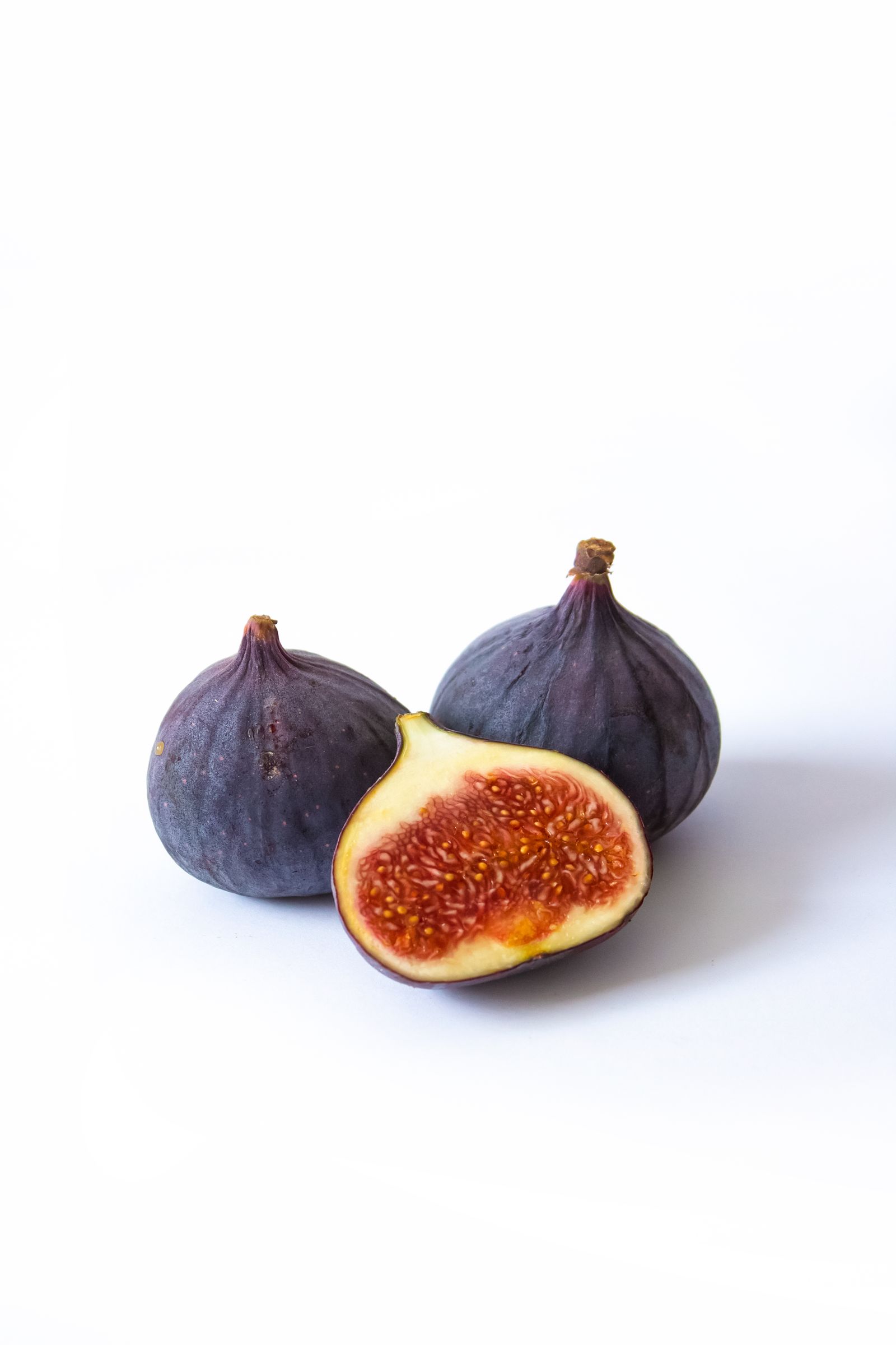 A fresh fig split open to reveal its deep crimson interior against a muted background