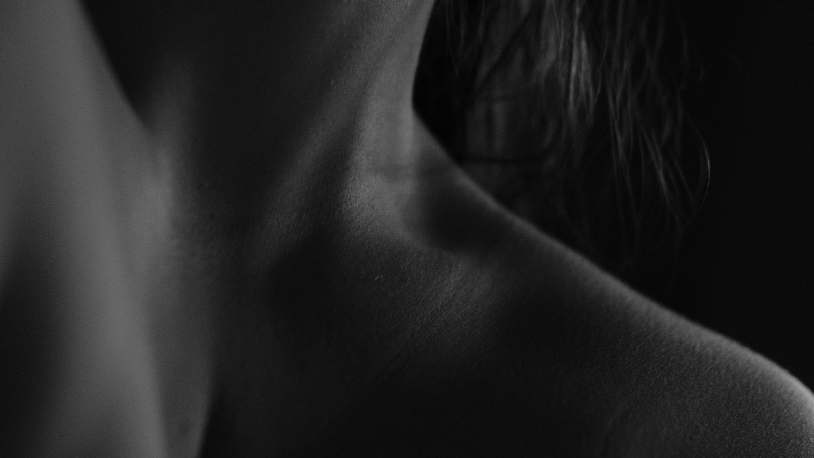 A bare shoulder and the line of a neck in low morning light, a study in shadow